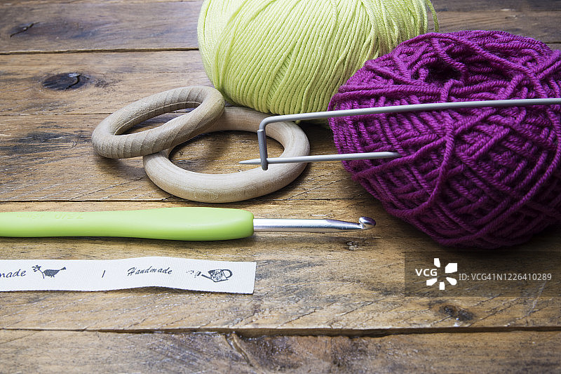 橙色和绿色棉线、钩针和木环在乡村木质背景上。复制空间图片素材