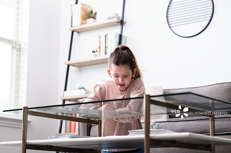 在家上学的前青少年女孩跪在咖啡桌旁做功课图片素材