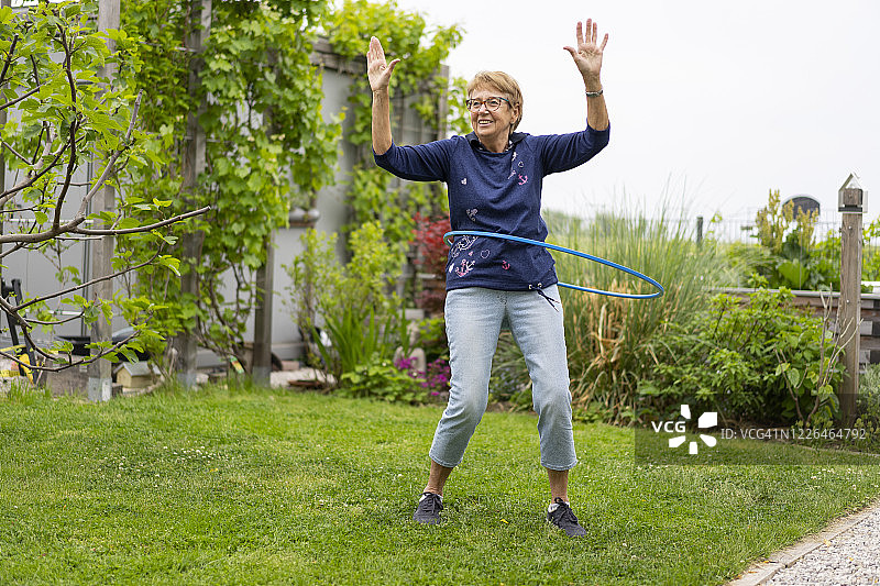 在花园里玩呼啦圈的快乐老年妇女图片素材