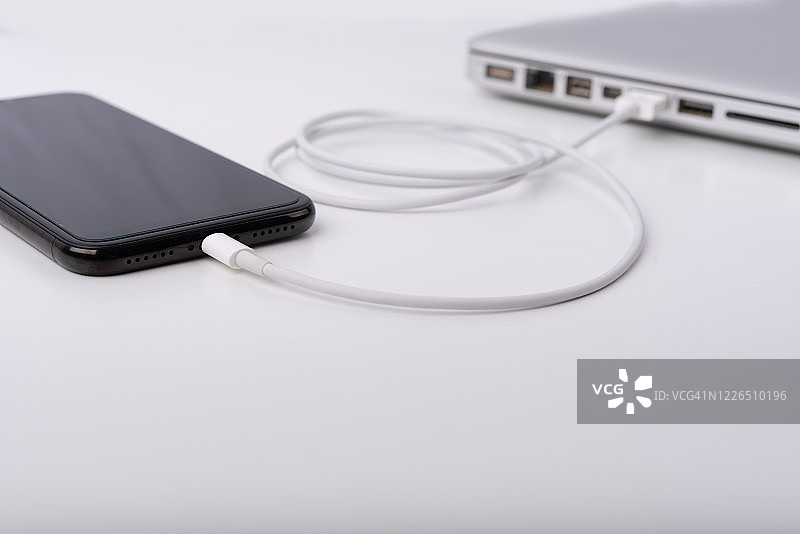 手机连接到笔记本电脑，隔离在白色背景上图片素材