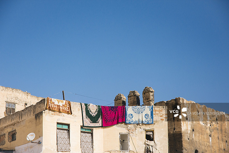 摩洛哥非斯：阳光明媚的日子里，住宅楼顶楼晾晒的彩色地毯图片素材