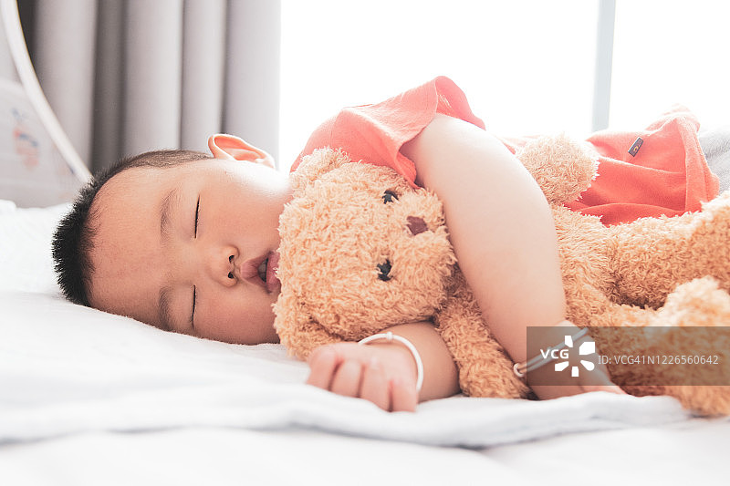 抱着泰迪熊睡觉的亚洲男婴图片素材