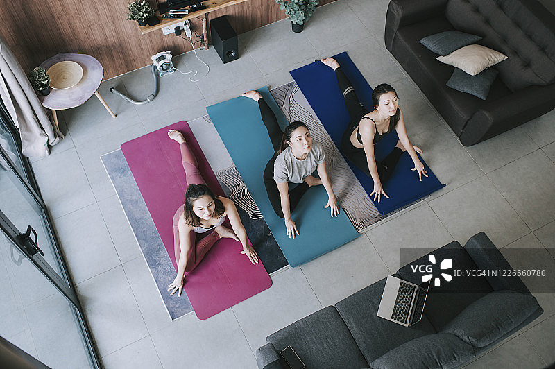 一群亚洲女性朋友在客厅一起使用笔记本电脑练习瑜伽网课图片素材