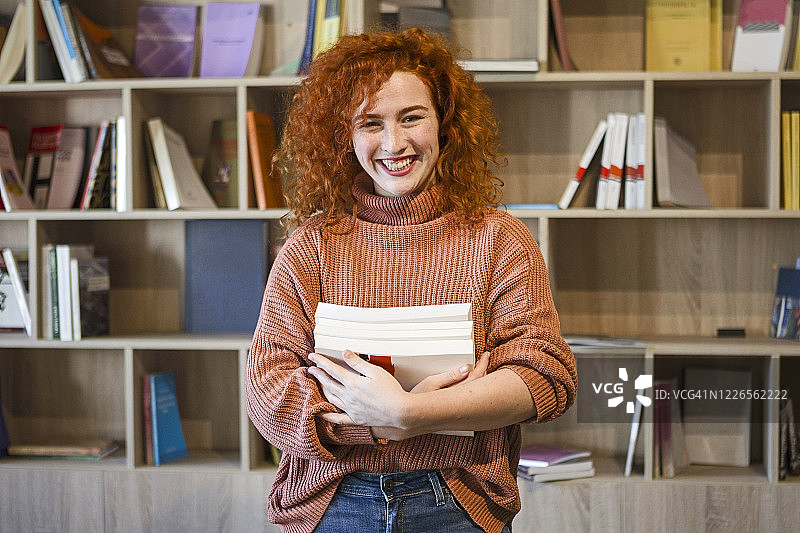 快乐的大学生在图书馆拿着书微笑图片素材