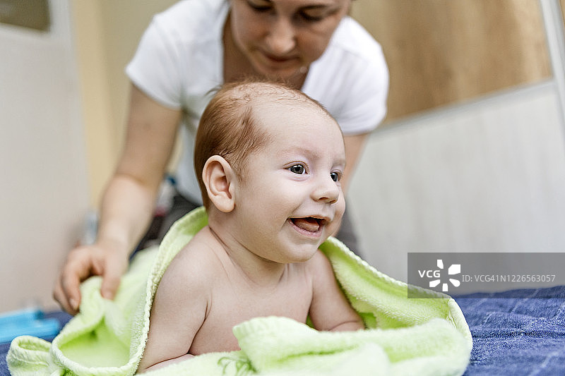 母亲在给新生儿洗澡后擦拭身体图片素材