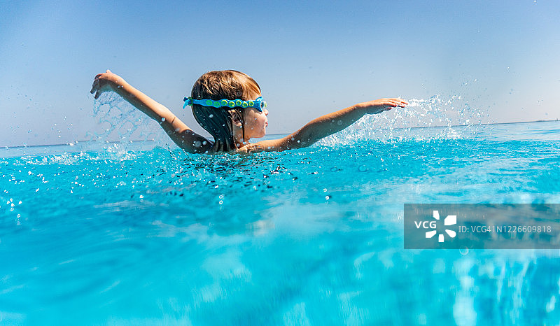 在游泳池里举起双手的男孩的背影图片素材