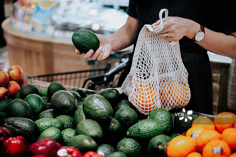 年轻亚洲女性在超市购买新鲜有机食品，使用棉网环保袋购物，零浪费理念图片素材