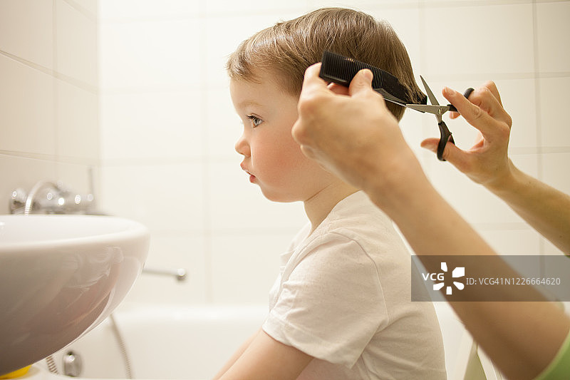 女人给3岁的儿子理发图片素材