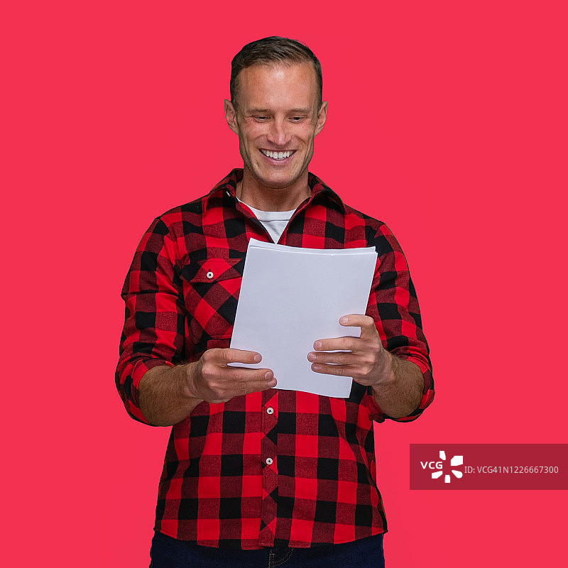 站在彩色背景前，拿着文件的白人男子图片素材