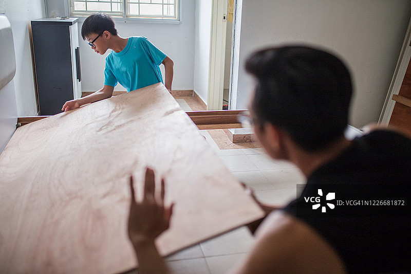 亚洲青少年帮助父亲安装家具，他们正在搬运和固定床具图片素材