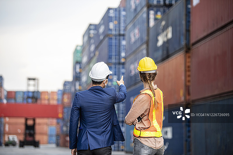 同事们站在堆放的货运集装箱前讨论工作图片素材