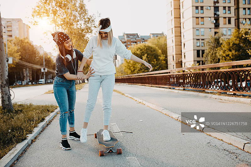 在城市里听音乐、玩滑板的年轻都市女孩图片素材