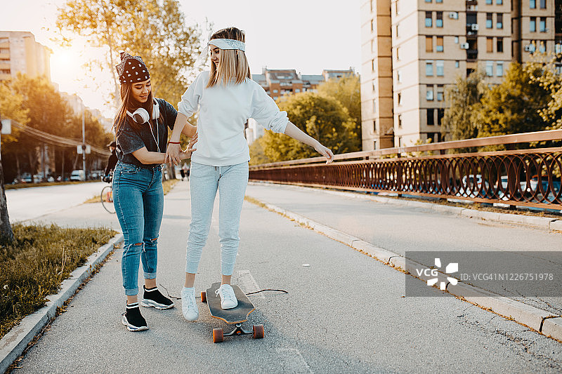 在城市里听音乐、玩滑板的年轻都市女孩图片素材