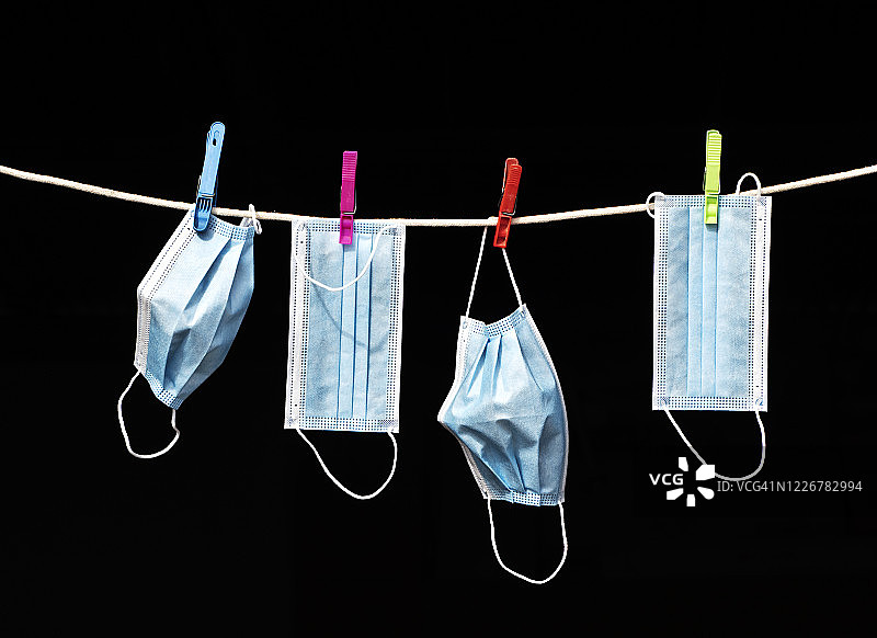 挂在黑色背景晾衣绳上的蓝色医用口罩图片素材