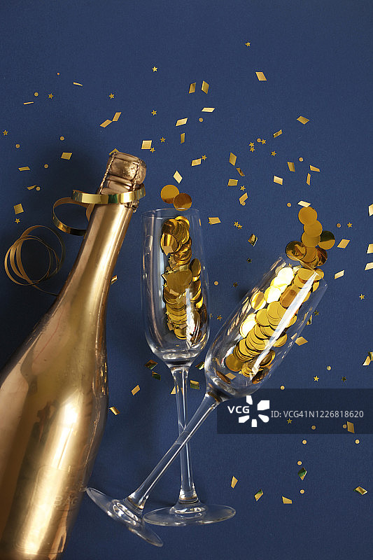 金色香槟酒瓶和深蓝色背景上的金色纸屑图片素材
