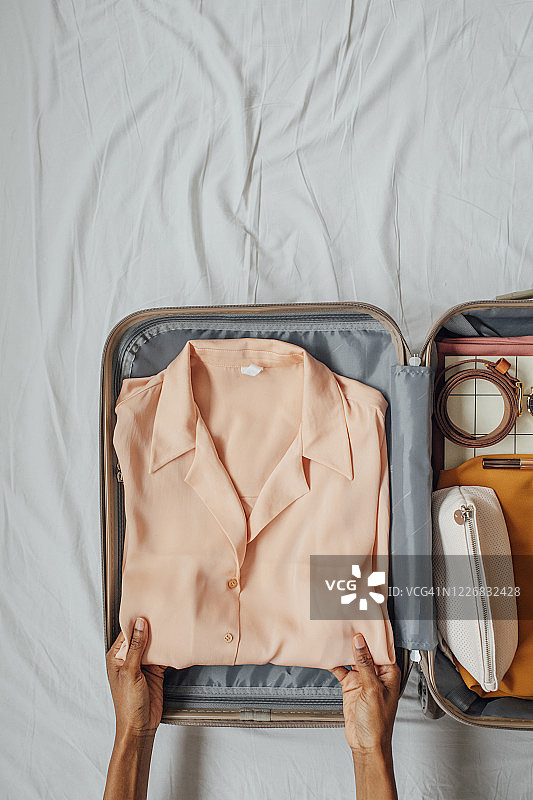 女子将衣服打包到行李箱里图片素材