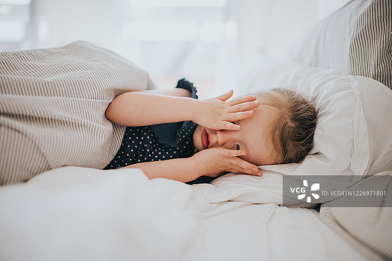 女孩在床上捂住眼睛图片素材