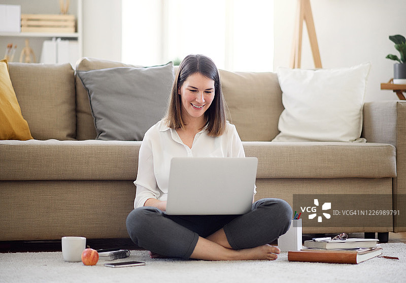 在家居办公室使用笔记本电脑工作的年轻女人，隔离概念图片素材