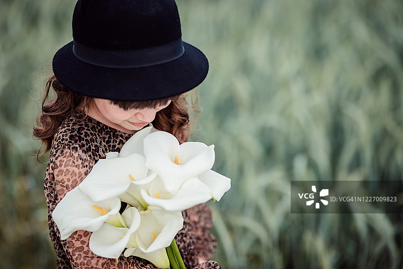 戴着帽子，怀抱百合花的女孩图片素材