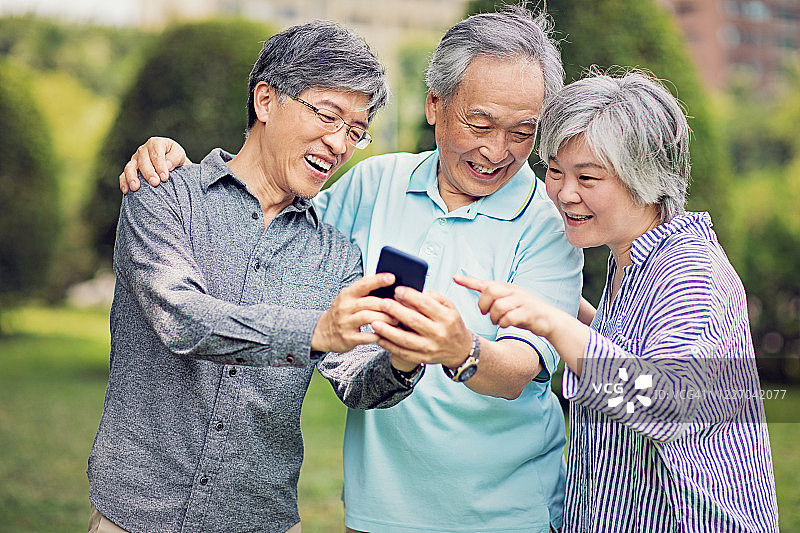 在公园里看手机的中年亚洲朋友图片素材
