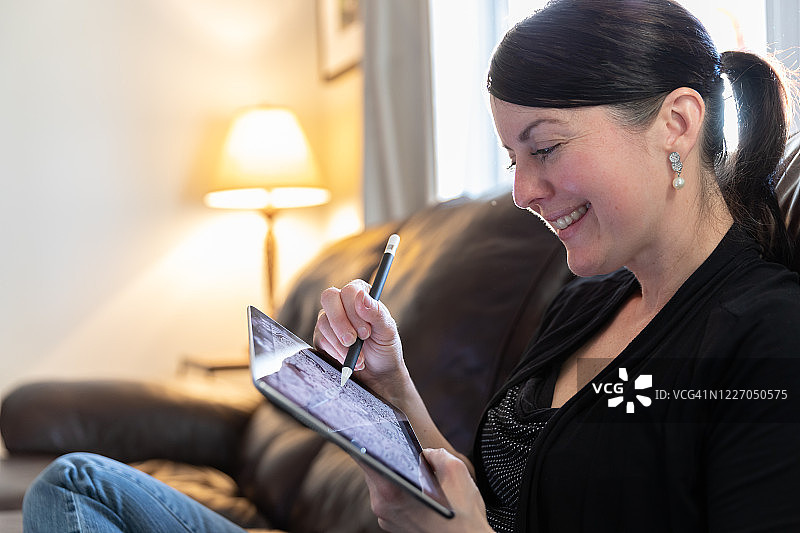 女子在客厅的数位板上绘画图片素材
