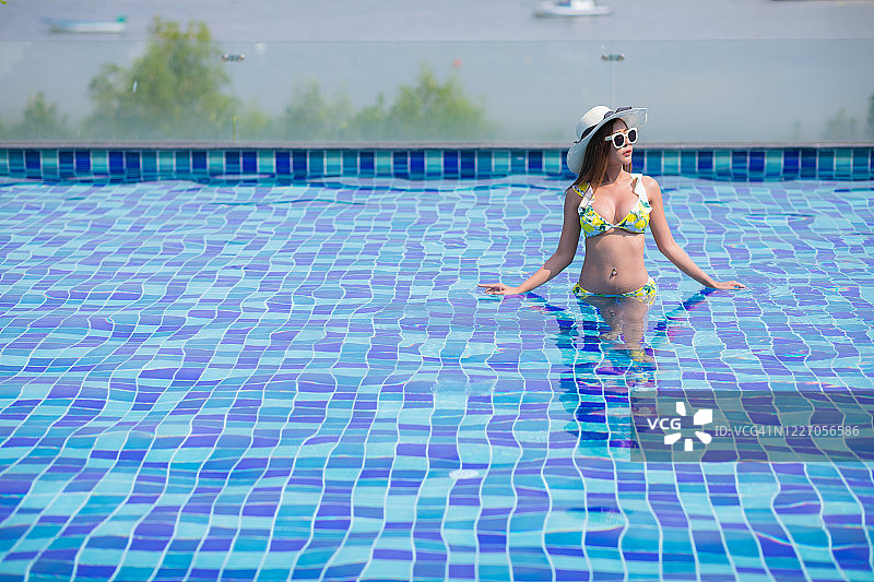 亚裔女性在泳池别墅放松身穿泳衣图片素材