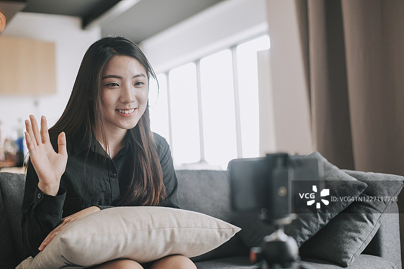中国视频博主在客厅沙发上用手机直播图片素材