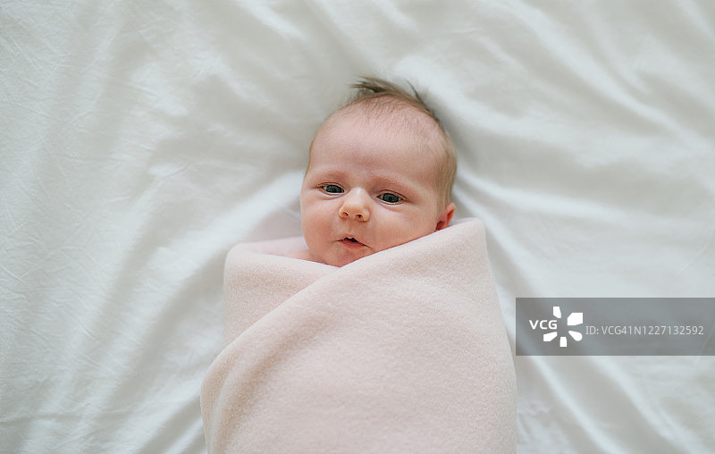 包裹着的新生女婴躺在床上的俯视图图片素材