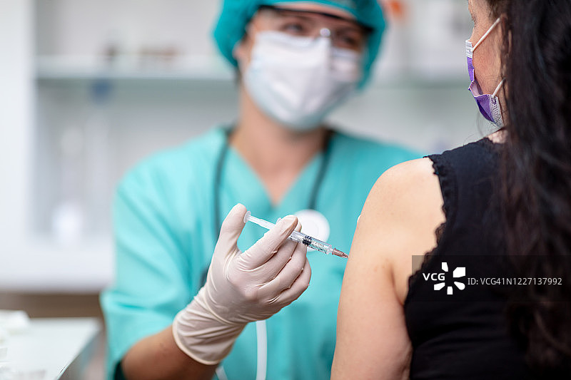 穿防护服的女医生给女病人注射疫苗图片素材