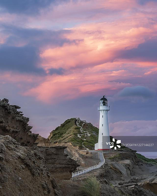 新西兰 Castlepoint 粉红色多云天空下悬崖上的灯塔图片素材