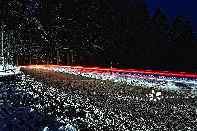德国，夜晚有红色光轨的雪路图片素材