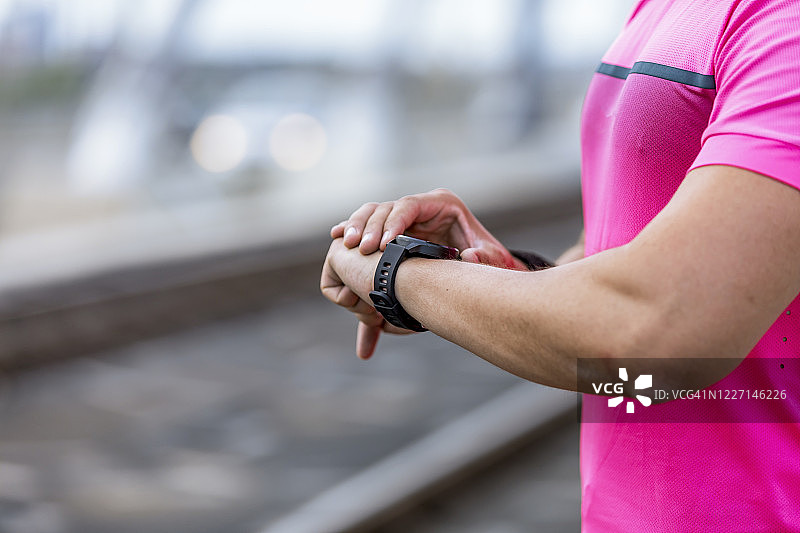 在山路上跑步的人查看智能手表或运动手表，检查GPS导航位置地图或心率脉冲轨迹，使用心率监测设备。在户外大自然中进行运动和健身。图片素材