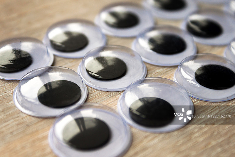 玩偶、玩具人造塑料眼睛在浅色天然木材上的抽象背景。 俯视图。 特写。图片素材