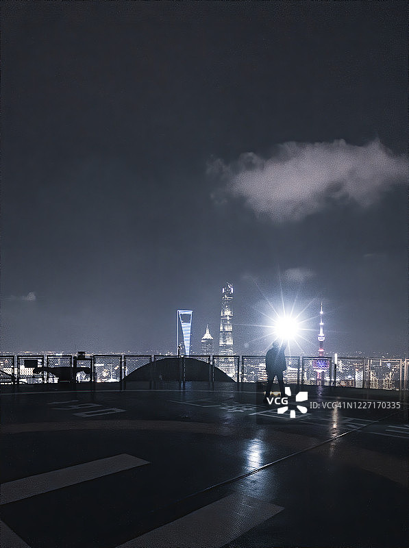 夜晚，男子用手机照亮城市天空的概念摄影图片素材