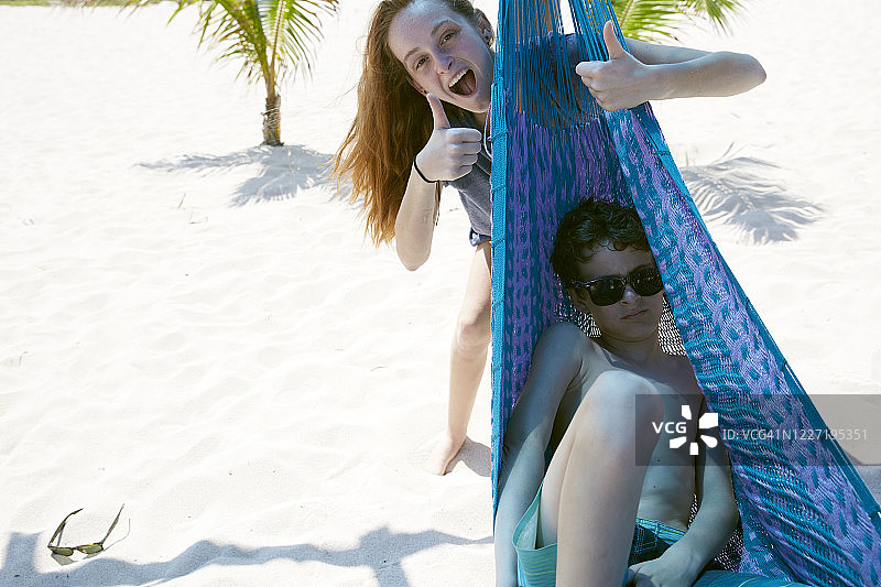 在墨西哥海滩，青少年姐弟在吊床上玩耍图片素材