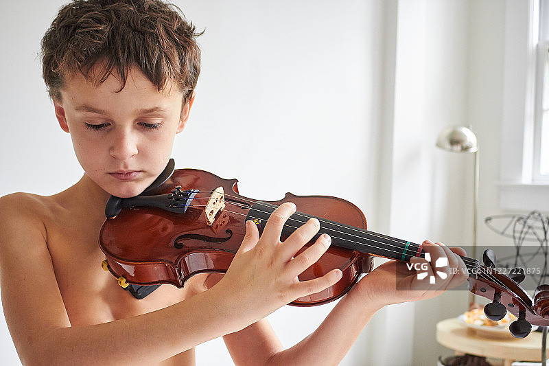男孩在家中赤裸上身拉小提琴特写图片素材