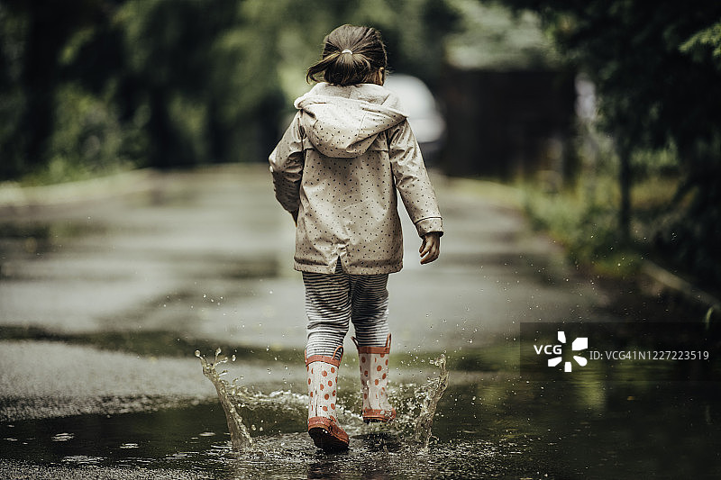 微笑的小女孩在水坑里玩耍图片素材