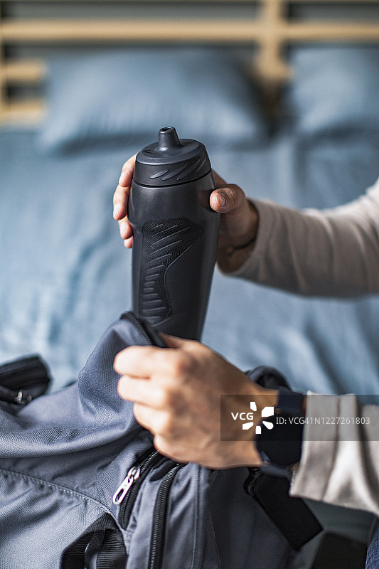 健康生活方式：在卧室里收拾运动包的年轻男人图片素材