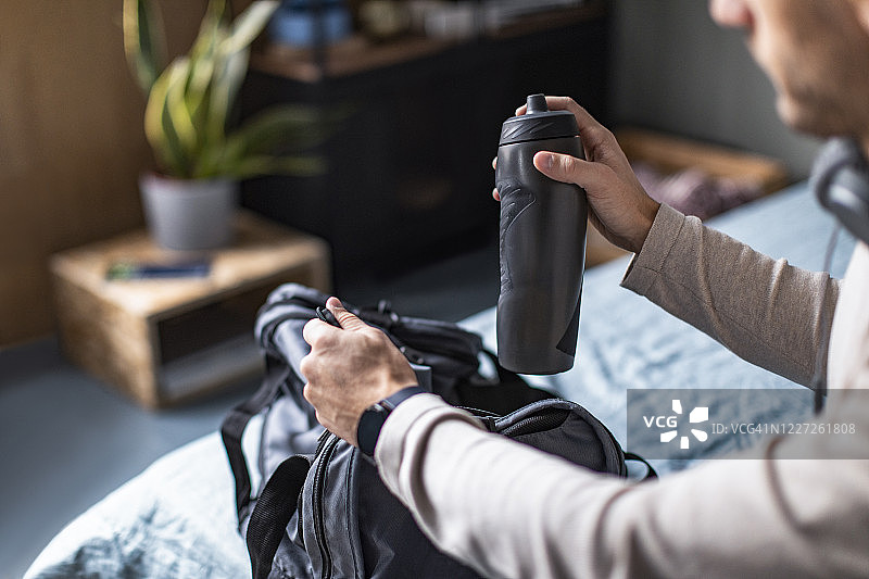 健康生活方式：在卧室里收拾运动包的年轻男人图片素材