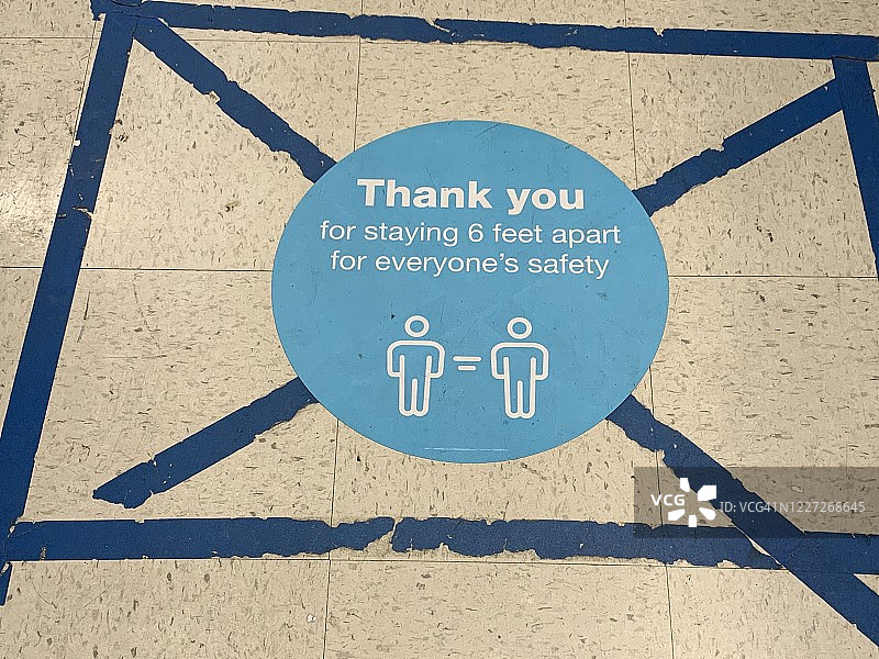 保持社交距离：新冠疫情期间，商店地面张贴的信息标牌图片素材