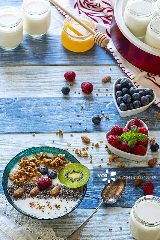 蓝色背景上的玻璃罐自制酸奶，配薄荷叶和蜂蜜图片素材