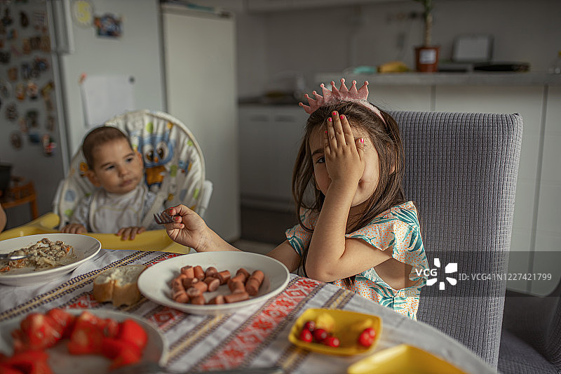 害羞的小孩边吃东西边遮住脸图片素材
