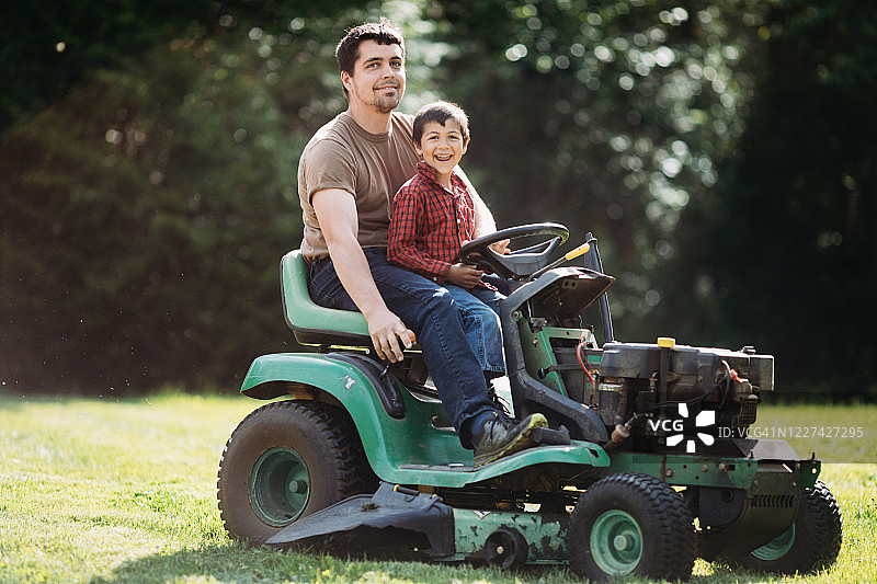 父亲和儿子在割草机上微笑图片素材