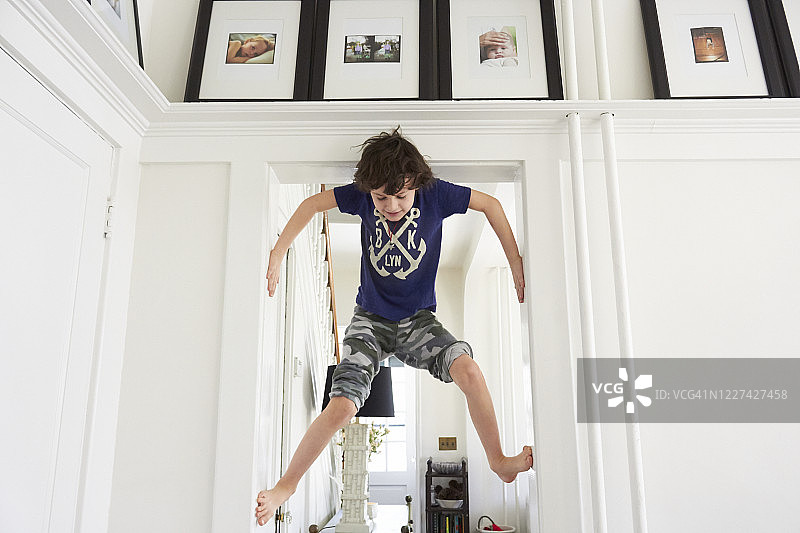 棕色卷发小男孩攀爬门框图片素材