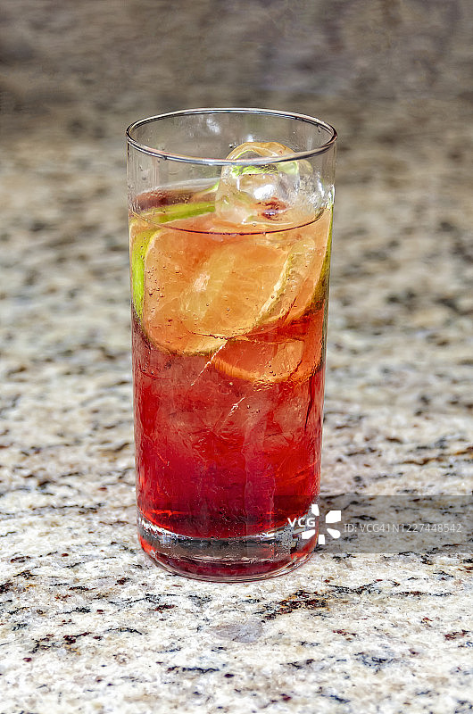 花岗岩台面上长玻璃杯中的红色酒精饮料图片素材