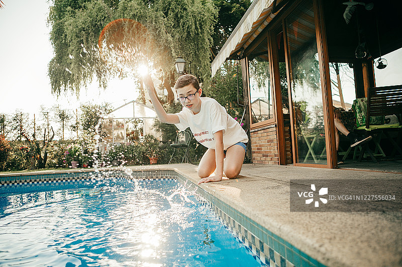 男孩在泳池边踢水花图片素材