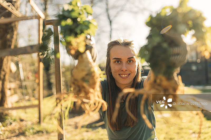 在花园里手持芹菜根的自豪年轻女子图片素材