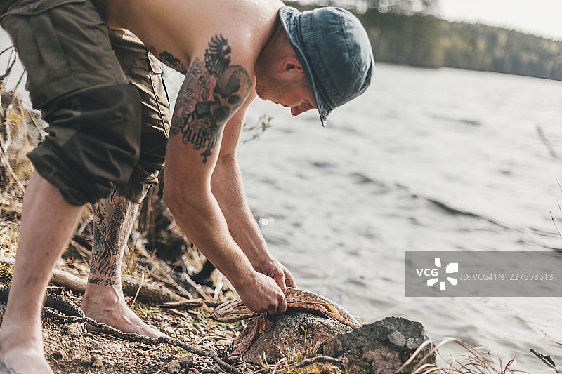 年轻男人在湖岸边处理鱼图片素材