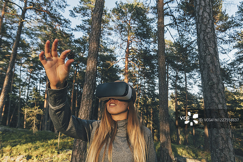 年轻女人在户外使用VR眼镜观察松果图片素材