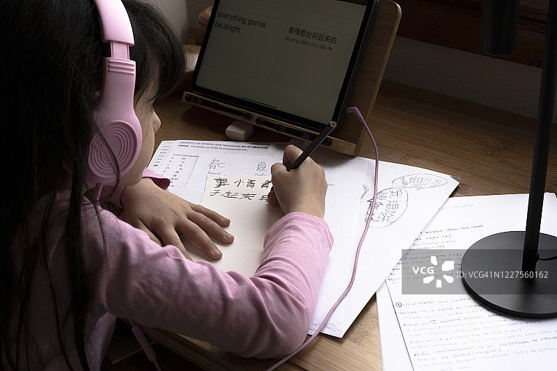 女孩戴着耳机，用平板电脑学习中文图片素材